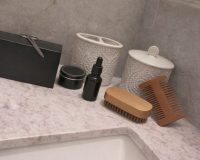 Tyylikkäitä kylpyhuonetarvikkeita marmoritasolla.